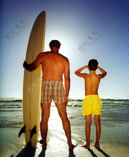 海滩上拿皮艇看海的父子图片