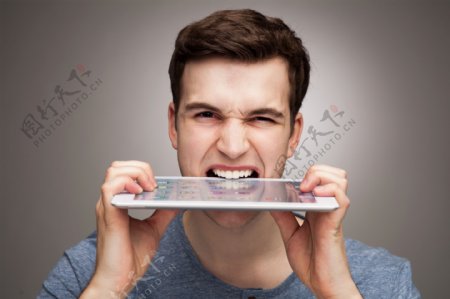 用牙齿咬平板电脑的外国男人图片
