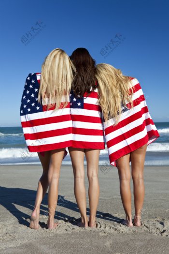 沙滩上披着国旗站着的外国美女背影图片