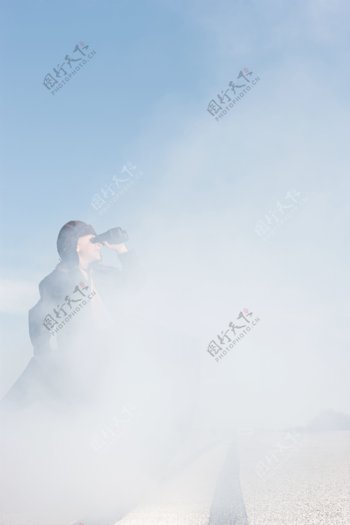 云雾中拿望远镜的小男孩图片