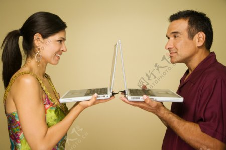 面对对端着电脑的情侣图片