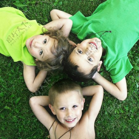 躺在草坪上头靠在一起的三个小孩图片