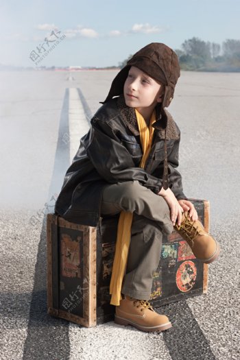 戴帽子男孩坐着行李箱上的男孩图片