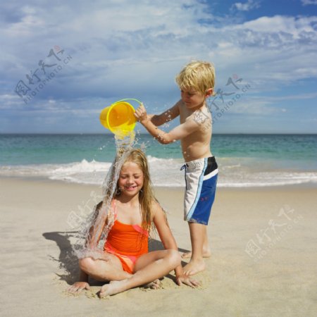 海滩沙滩浇水的小姐弟图片