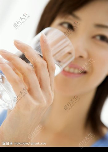 女性用透明的玻璃杯子喝水图片
