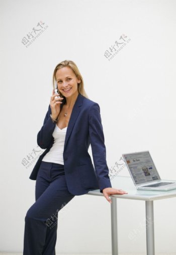 在电脑旁打电话的美女图片