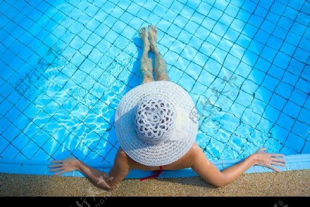 游泳池边休闲度假的太阳帽女人图片