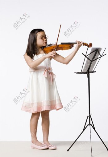看着乐谱拉小提琴的小女孩图片