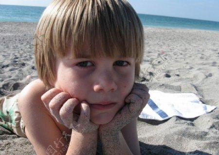 沙滩上托着下巴的男孩图片
