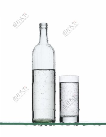 玻璃板上的一瓶水和一杯水图片