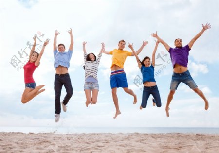 沙滩上跳跃的外国男女图片