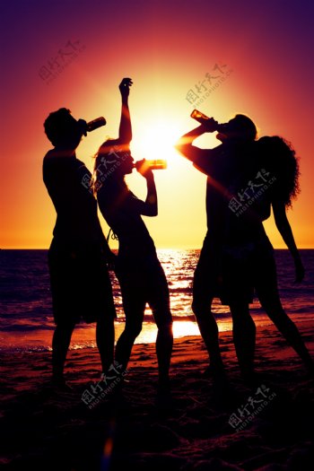 夕阳下在海边喝酒的外国男女图片