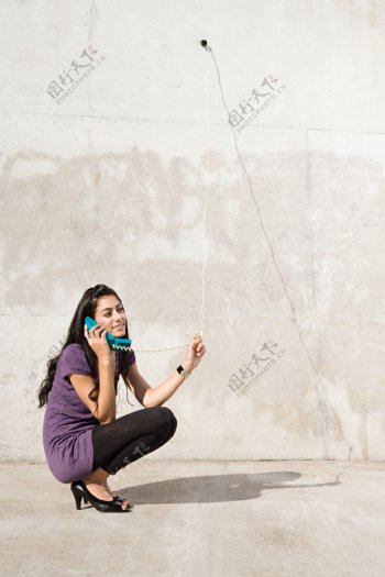 蹲在墙角打电话的女人图片