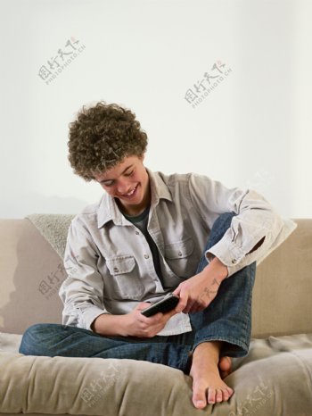 坐在沙发上玩手机的外国男人图片