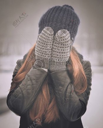 女人在灰色针织帽捂住脸灰色针织手套