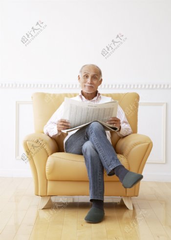 坐在沙发上看报纸的老人图片