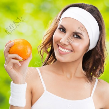 手拿橙子的健身女性图片