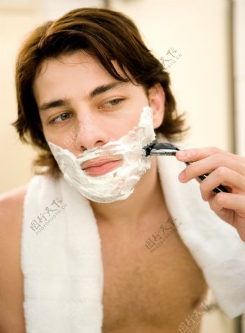 拿着剃须刀刮胡须的男人图片