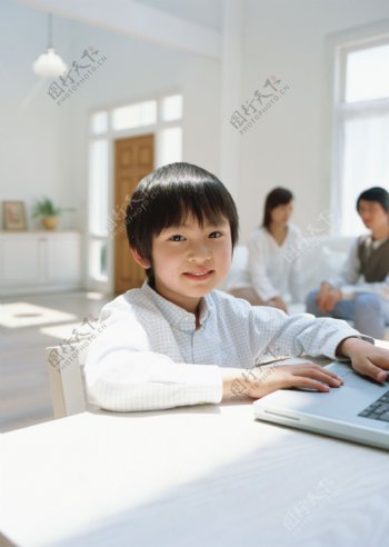 坐在电脑旁的小男孩图片