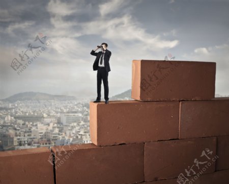 站在砖墙上用望远镜的商务人图片