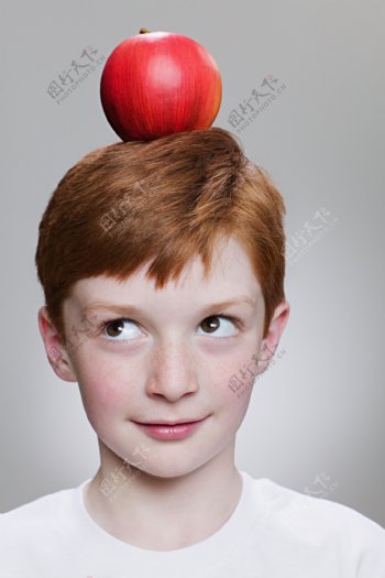 小男孩看头顶上的红苹果图片