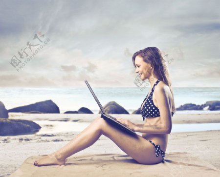 坐在沙滩上玩电脑的女人图片